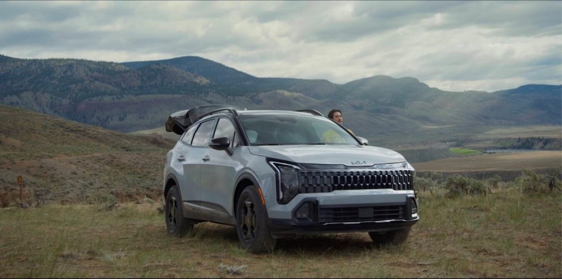 A man standing beside a gray 2026 Kia Sportage Hybrid SUV