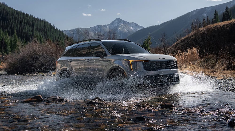 A gray 2026 Kia Sorento SUV splashing through a shallow river