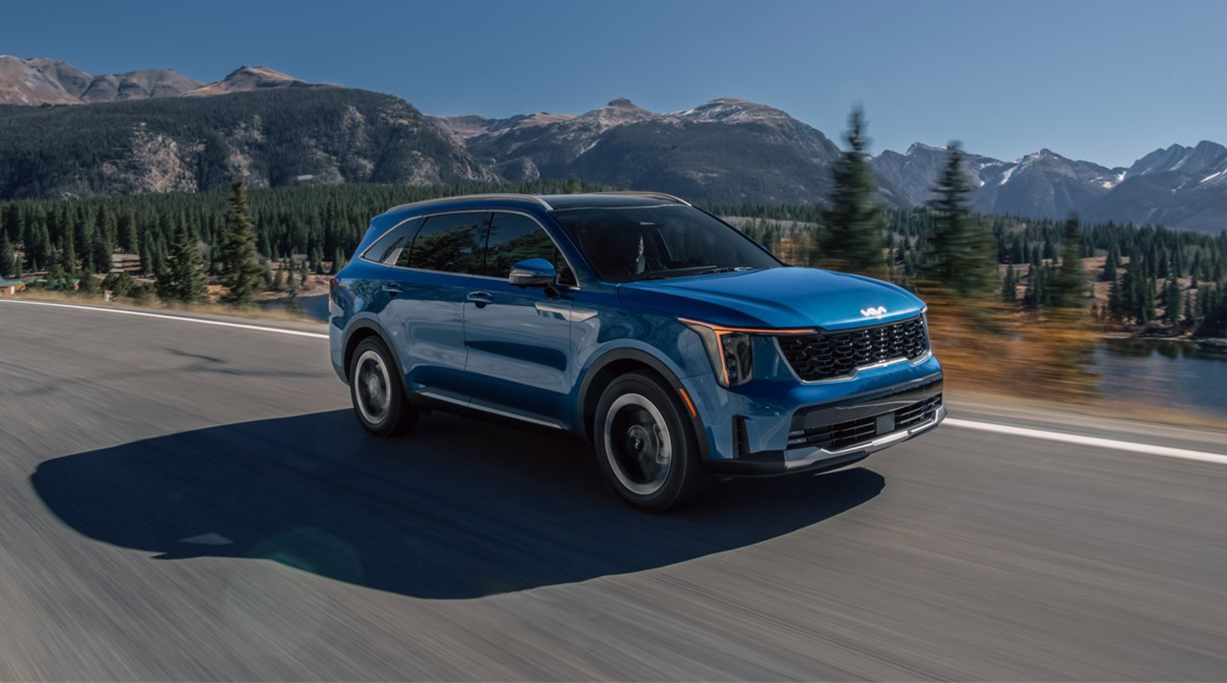 2025 Kia Sorento Hybrid on the road with mountains and trees in the background