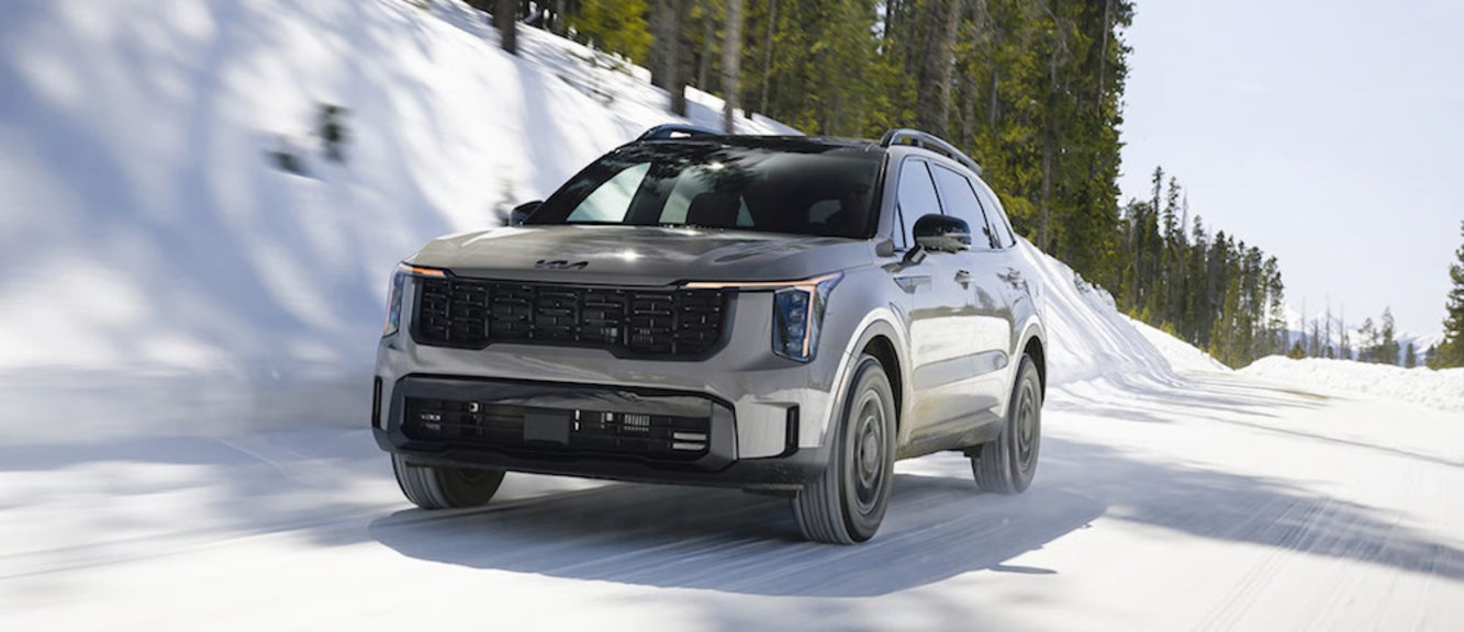 A gray 2026 Kia Sorento SUV driving down a snowy road