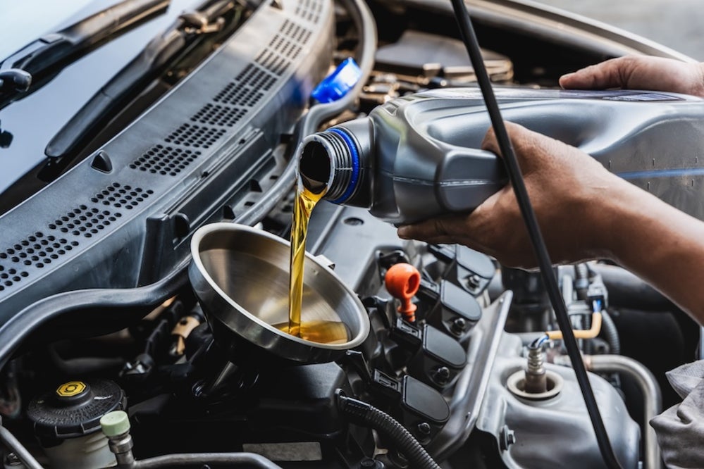A mechanic pouring engine oil into a car’s engine
