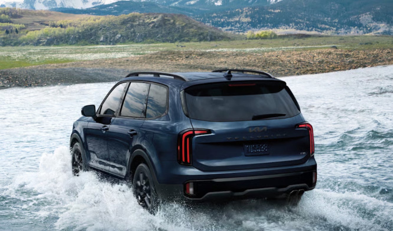 A dark blue 2025 Kia Telluride SUV crossing a river
