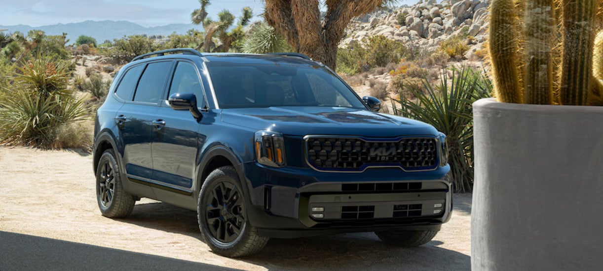 A blue 2025 Kia Telluride parked near some cacti